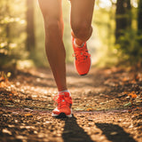 A close-up action shot of a runner's feet in vibrant orange trainers, mid-stride on a sunlit forest trail.