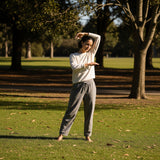 Person gently stretching outdoors in a park, symbolizing comfort and fluid movement for an active lifestyle.