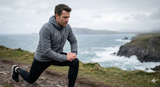 A runner stretching their knee on a coastal path, demonstrating runner's knee recovery exercises and injury prevention.