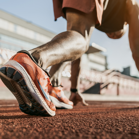 Track athlete in OOST orange shoes on the starting blocks showing Enhanced Flexibility and Explosive Power Output