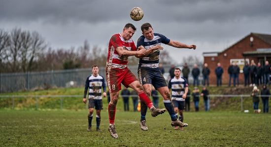 Football players contesting an aerial header during a club match