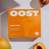 A carton of OOST surrounded by peaches and mango